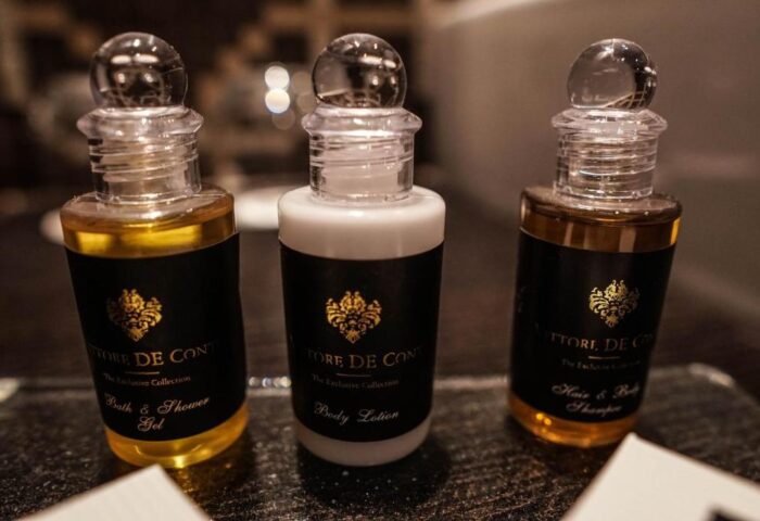Continental Hotel toiletries. Bath gel, body lotion, and shampoo bottles on a tray. Gay-friendly hotel amenities for a comfortable stay.
