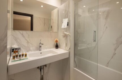 Continental Hotel bathroom. Sink, mirror, and shower in a modern, bright space. Gay-friendly hotel with upscale amenities.