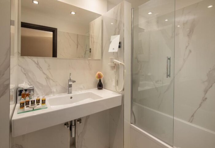 Continental Hotel bathroom. Sink, mirror, and shower in a modern, bright space. Gay-friendly hotel with upscale amenities.