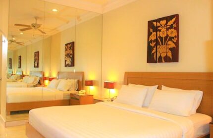 Gay-friendly Copa Hotel bedroom with a king-size bed, bedside lamps, and a decorative floral painting. Mirror wall. Gay travel lodging.