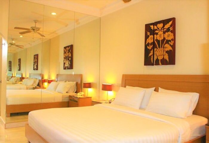 Gay-friendly Copa Hotel bedroom with a king-size bed, bedside lamps, and a decorative floral painting. Mirror wall. Gay travel lodging.