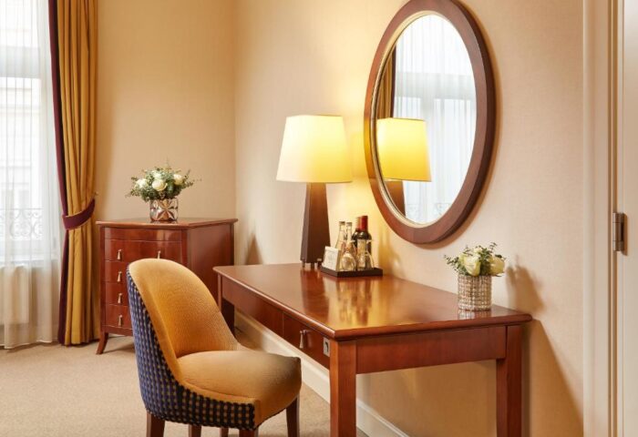 Corinthia Hotel Budapest room detail. Desk, chair, mirror, and flowers. Gay-friendly, pet-friendly hotel interior. Budapest travel advice.