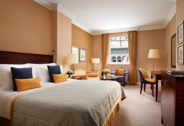 Hotel room at Corinthia Hotel Budapest. Gay-friendly, pet-friendly hotel with a large bed, sitting area, desk, and window.