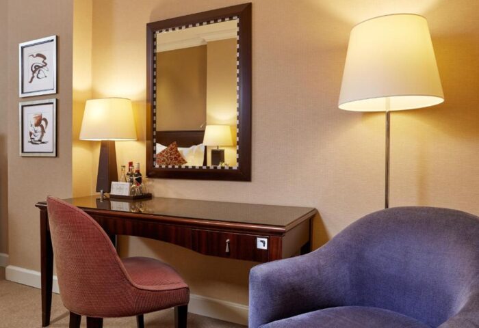 Corinthia Hotel Budapest room detail. Desk with mirror, chair, and lamp. Gay-friendly, pet-friendly hotel room interior.