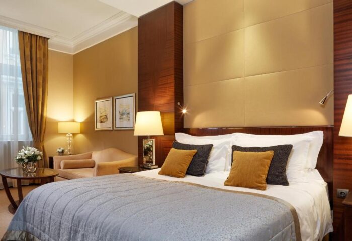 Corinthia Hotel Budapest room. Gay-friendly, pet-friendly hotel with a large bed, pillows, a sofa, and a table with flowers.