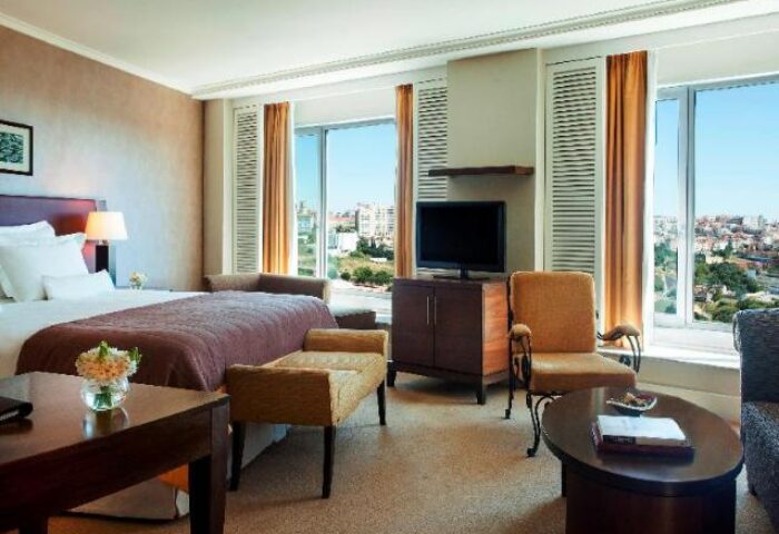 Corinthia Hotel Lisbon room. Gay-friendly, pet-friendly hotel with bed, TV, seating, and a view of Lisbon. Ideal for gay travel.