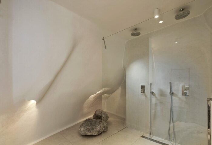 Cosmopolitan Suites gay-friendly hotel bathroom. Modern shower with unique wall design and stone accents. Luxury gay travel accommodation.