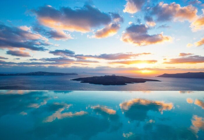 Sunset view from Cosmopolitan Suites, a gay-friendly hotel. Infinity pool reflects the sky over the Aegean Sea. Ideal for gay travel.