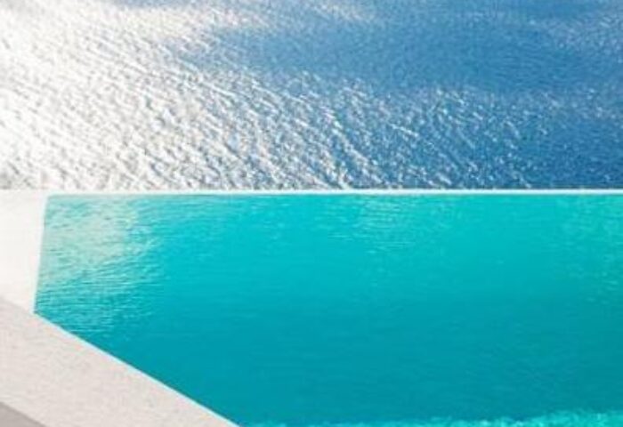 Infinity pool overlooking the sea at Cosmopolitan Suites, a gay-friendly hotel. Turquoise water blends with the ocean horizon. Serene travel destination.