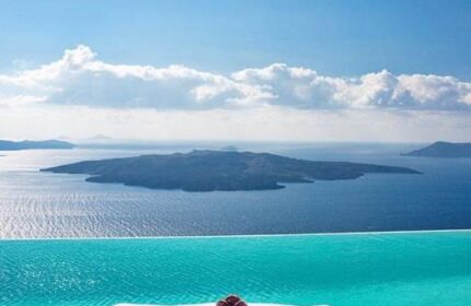 Cosmopolitan Suites gay-friendly hotel view. Infinity pool overlooking the Aegean Sea and volcanic islands. Luxury travel for gay men in Santorini.