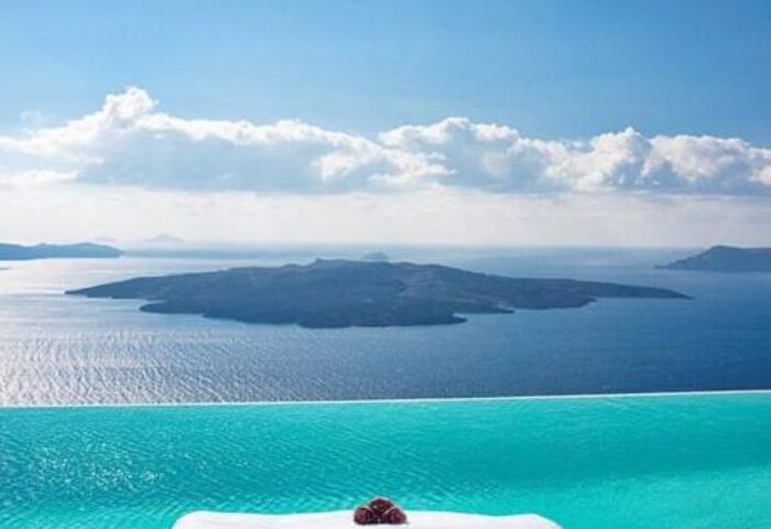 Cosmopolitan Suites gay-friendly hotel view. Infinity pool overlooking the Aegean Sea and volcanic islands. Luxury travel for gay men in Santorini.