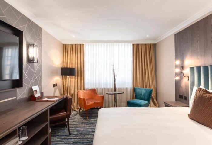 Courthouse Hotel bedroom with desk, TV, and chairs. Gay-friendly, pet-friendly hotel room interior. Comfortable stay for gay travelers.