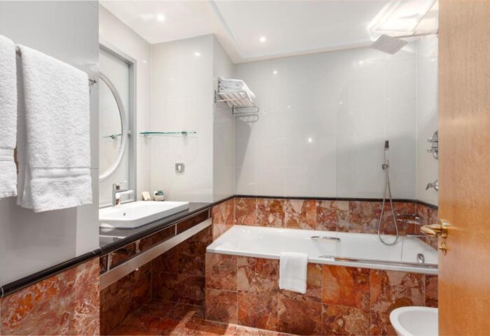 Courthouse Hotel's pet-friendly bathroom. This gay-friendly hotel features a tub, shower, sink, mirror, and marble tile. Great for gay travel.