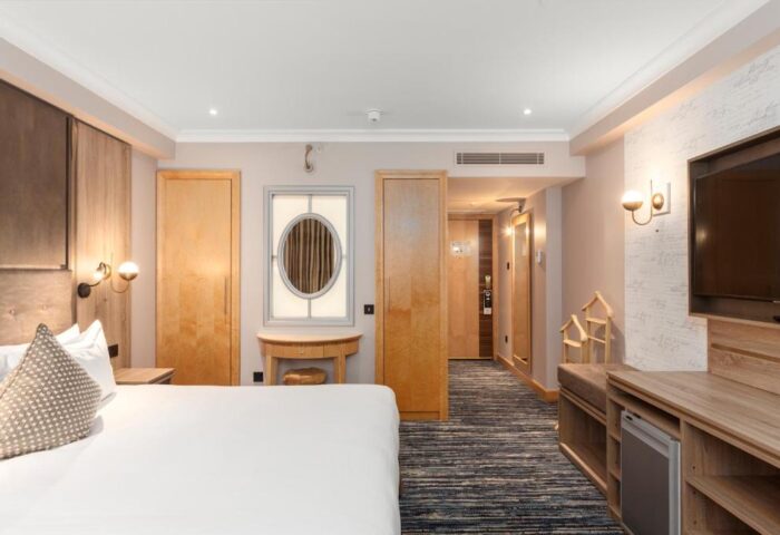 Courthouse Hotel bedroom interior. Gay-friendly, pet-friendly hotel room with bed, TV, mirror, and closet. Modern design.