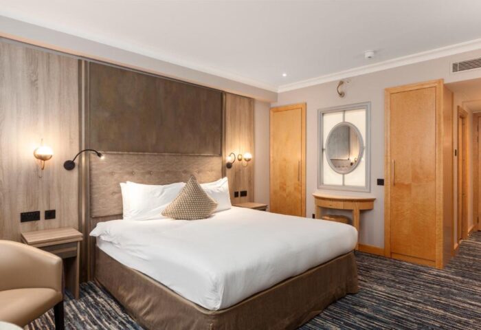 Courthouse Hotel bedroom. Gay-friendly, pet-friendly hotel room with bed, wardrobe, mirror, and chair. Ideal for gay men travel.