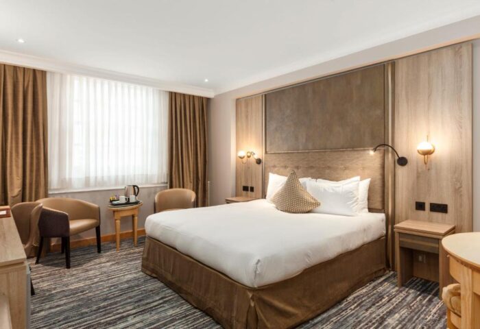 Courthouse Hotel gay-friendly room. Pet-friendly hotel with a king-size bed, bedside tables, lamps, chairs, and a window with curtains.