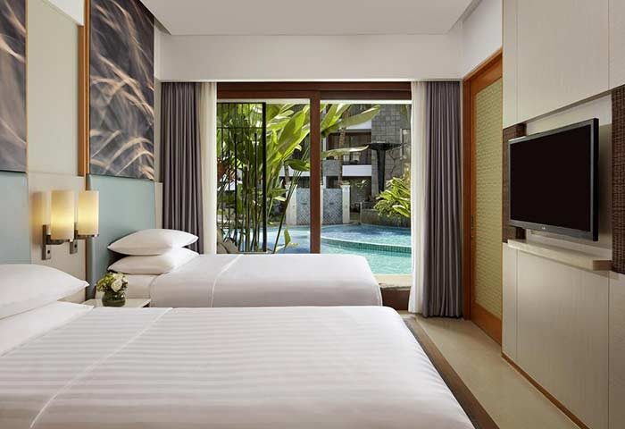 Courtyard Bali Seminyak Resort room with two beds, TV, and pool view. Gay-friendly hotel for gay men traveling to Bali.