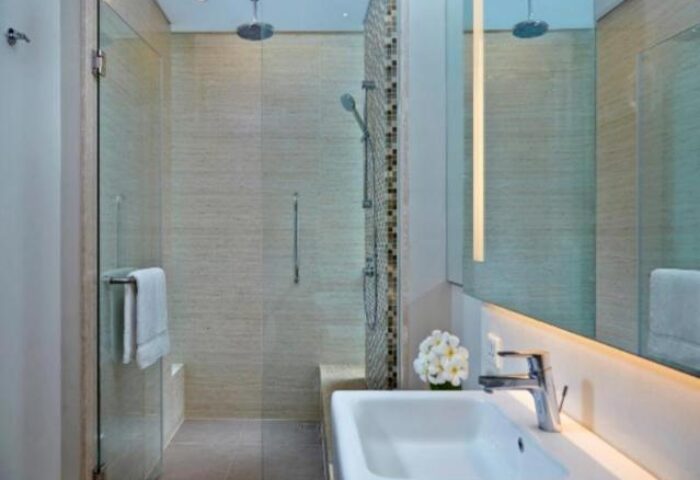 Bathroom at Courtyard Bali Seminyak Resort, a gay-friendly hotel. Features a walk-in shower, modern sink, and large mirror.