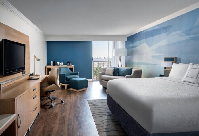 Courtyard Long Beach Downtown gay-friendly hotel room. King bed, desk, TV, sofa, and balcony. Modern design and comfortable amenities.