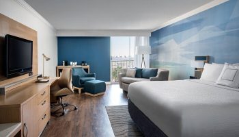 Courtyard Long Beach Downtown gay-friendly hotel room. King bed, desk, TV, sofa, and balcony. Modern design and comfortable amenities.