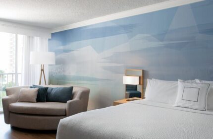 Courtyard Long Beach Downtown hotel room. Gay-friendly hotel with a bed, couch, and blue wall art. Modern design for gay travelers.