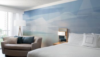Courtyard Long Beach Downtown hotel room. Gay-friendly hotel with a bed, couch, and blue wall art. Modern design for gay travelers.