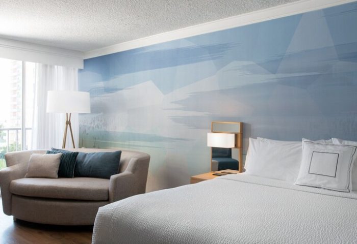 Courtyard Long Beach Downtown hotel room. Gay-friendly hotel with a bed, couch, and blue wall art. Modern design for gay travelers.