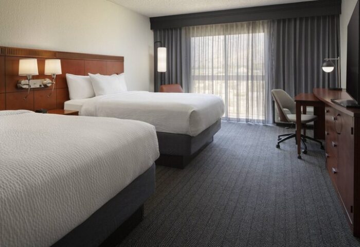 Courtyard Palm Springs gay-friendly hotel room with two beds, desk, chair, and window. A comfortable stay for gay travelers.