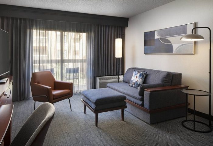 Courtyard Palm Springs gay-friendly hotel room. Living area with sofa, chair, ottoman, and modern decor. Comfortable stay for gay travelers.