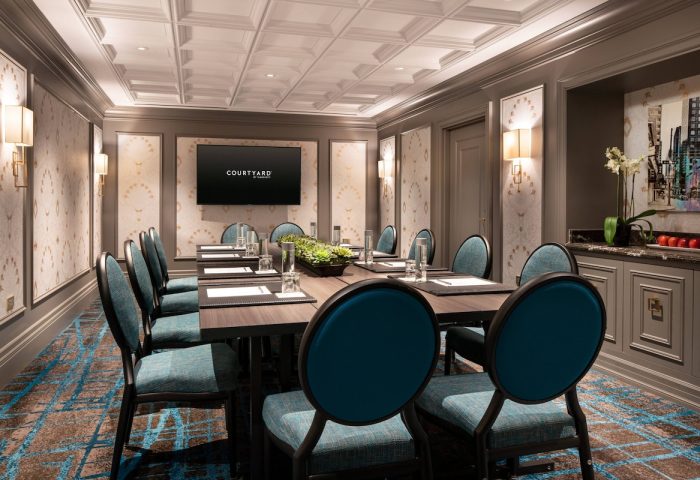 Courtyard San Francisco Downtown/Van Ness Ave meeting room. Boardroom table with blue chairs, TV screen, and modern decor. Gay-friendly hotel.