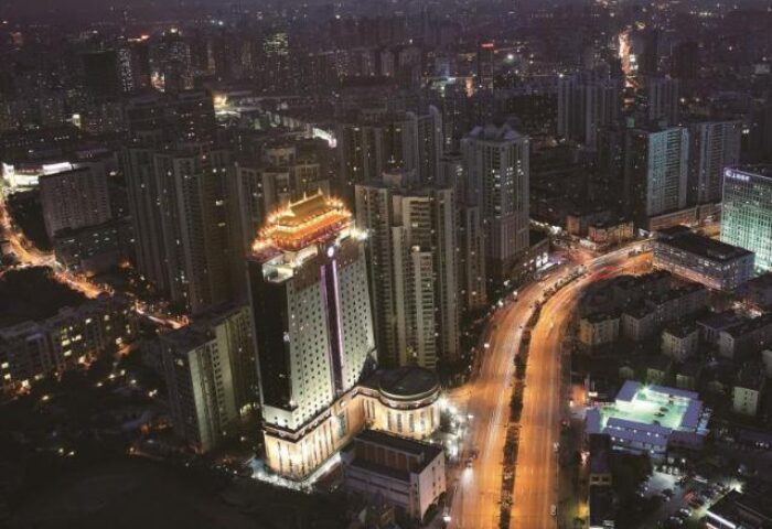 Night view of Courtyard by Marriott Shanghai Xujiahui, a gay-friendly hotel. Aerial shot of city lights and hotel with traditional Chinese roof.
