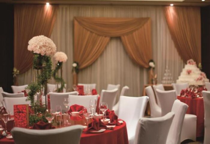 Courtyard by Marriott Shanghai Xujiahui gay-friendly hotel ballroom setup for a wedding. Tables with red cloths, white chairs, cake.