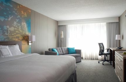 Courtyard by Marriott Toronto Downtown hotel room. Gay-friendly accommodations with a king bed, sofa, desk, and modern decor.