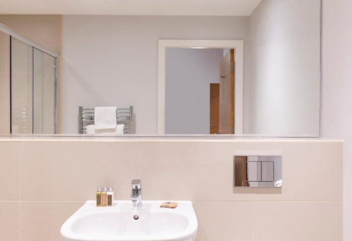 Cove Minshull Street gay-friendly hotel bathroom. Sink, mirror reflecting shower, towel rack, and toilet. Modern design for gay travelers.