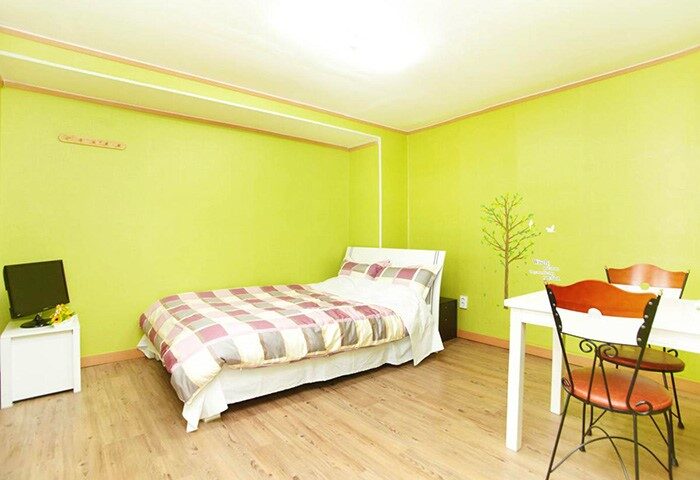 CozyPlace Guesthouse in Itaewon: Gay-friendly hotel room with a bed, table, chairs, and TV. A comfortable stay for gay travelers in Seoul.
