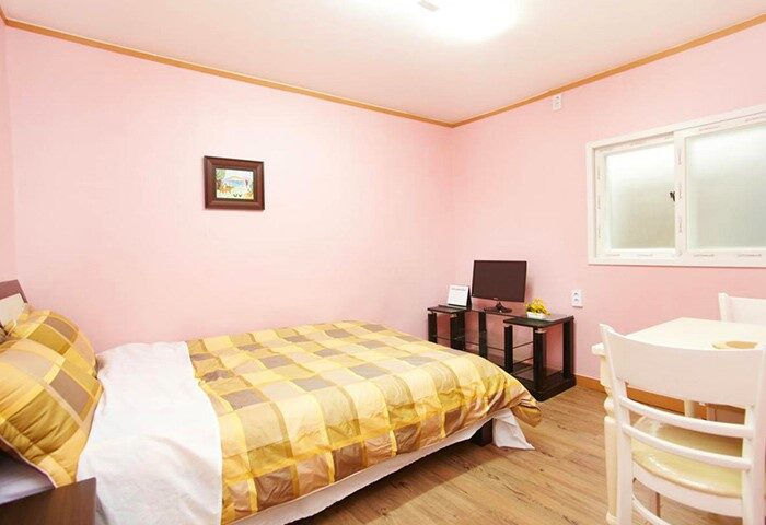 CozyPlace Guesthouse in Itaewon: Gay-friendly hotel room with a bed, TV, and table. A comfortable and inviting space for gay travelers.