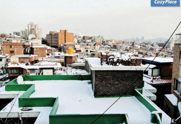 Snowy rooftop view from CozyPlace Guesthouse in Itaewon, Seoul. Gay-friendly hotel with city skyline. Winter travel in South Korea.