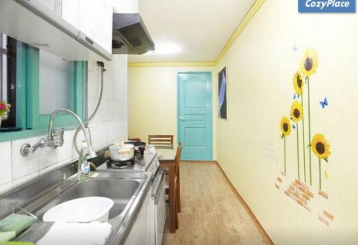 CozyPlace Guesthouse in Itaewon kitchen. Gay-friendly hotel with sunflower wall art. Budget travel for gay men in Seoul, South Korea.