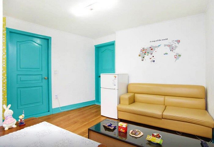 CozyPlace Guesthouse in Itaewon, a gay-friendly hotel. Room interior with sofa, fridge, map of the world, and colorful doors. Comfortable stay.