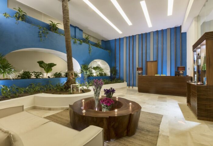 Crown Paradise Golden All Inclusive Adults Only gay-friendly hotel lobby. Modern design with blue walls, plants, and unique wood furniture.