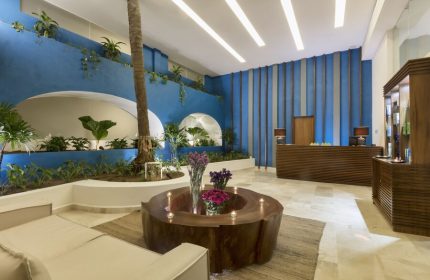 Crown Paradise Golden All Inclusive Adults Only gay-friendly hotel lobby. Modern design with blue walls, plants, and unique wood furniture.