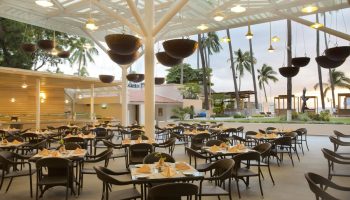 Crown Paradise Golden All Inclusive Adults Only gay-friendly hotel restaurant. Tables set for dining, palm trees in background.
