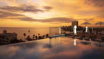 Sunset view from the rooftop pool at Crown Paradise Golden All Inclusive Adults Only, a gay-friendly hotel. Ocean, city skyline.