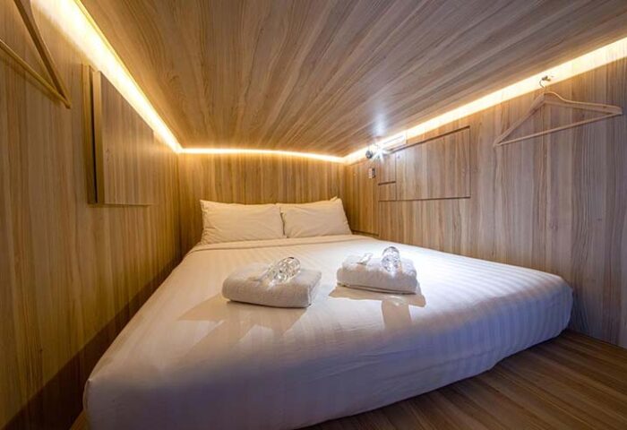 Cube Boutique Capsule Hotel @ Chinatown interior. Gay-friendly hotel capsule with double bed, towels, and wooden walls. Chinatown lodging.