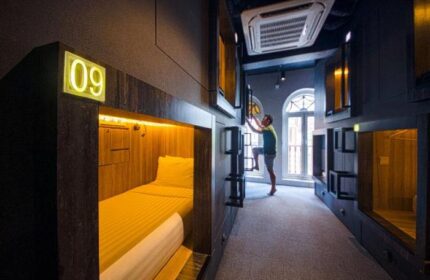 Cube Boutique Capsule Hotel @ Chinatown interior. Gay-friendly hotel room with pod beds. Man climbing ladder to top bunk. Chinatown lodging.