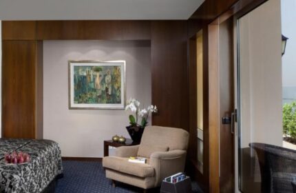 Dan Tel Aviv Hotel room. Gay-friendly hotel with a bed, chair, painting, orchids, and balcony. Modern design for gay travelers.