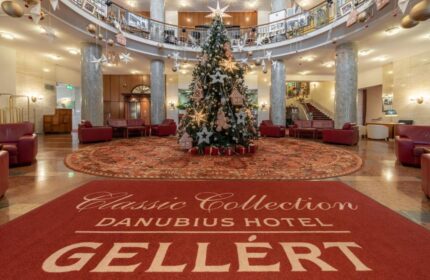 Danubius Hotel Gellert lobby with Christmas tree. Gay-friendly hotel in Budapest, Hungary. Interior with red carpets and seating areas.