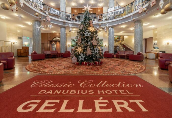 Danubius Hotel Gellert lobby with Christmas tree. Gay-friendly hotel in Budapest, Hungary. Interior with red carpets and seating areas.