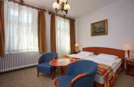 Danubius Hotel Gellert room. Gay-friendly hotel bedroom with twin beds, blue chairs, and a round table. Comfortable stay for gay travelers.