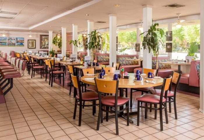Dining area at Days Inn by Wyndham Palm Springs, a gay-friendly hotel. Tables, chairs, booths, and a breakfast bar are available.